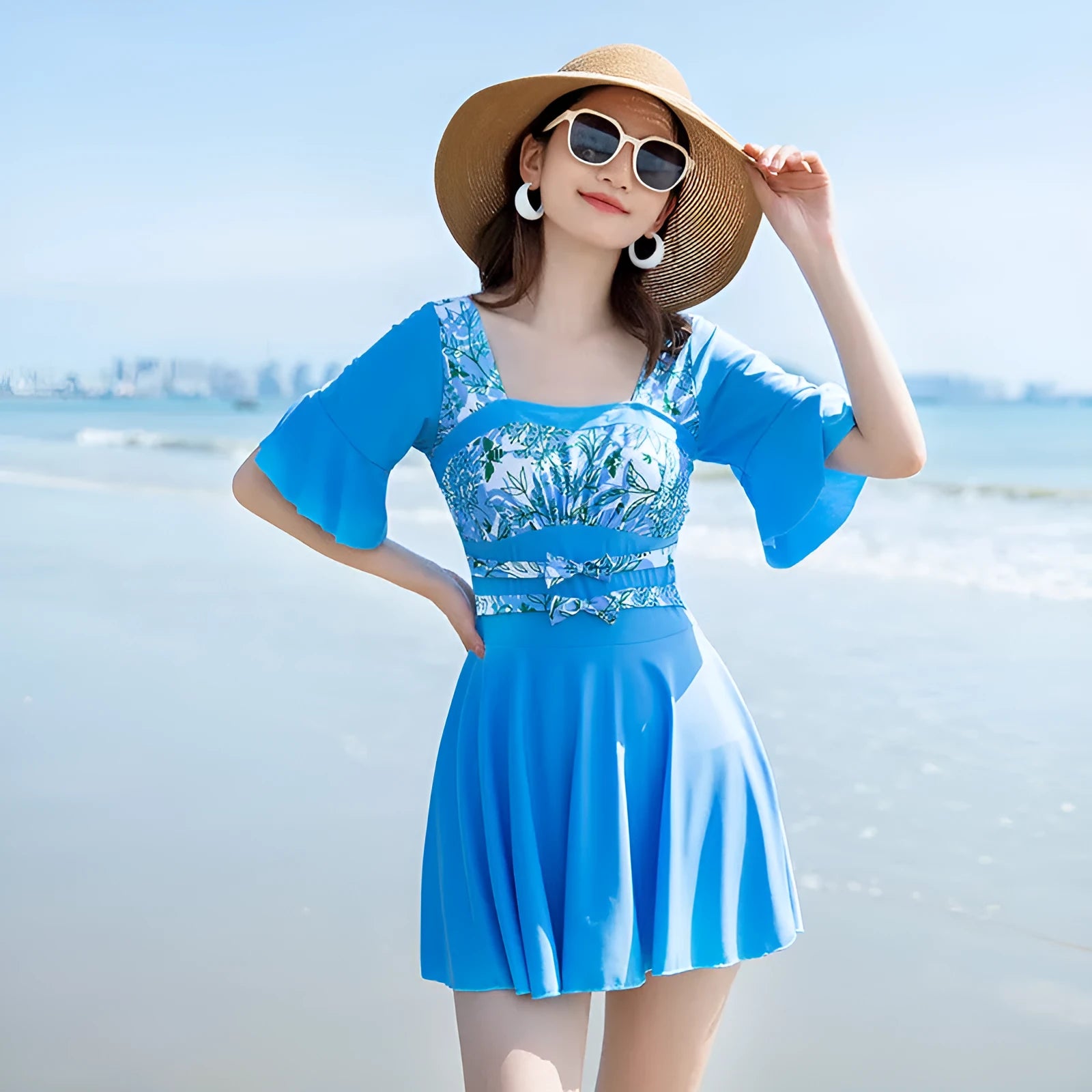Green and blue women's one-piece swimsuit with a printed seaside pattern on a mannequin.
