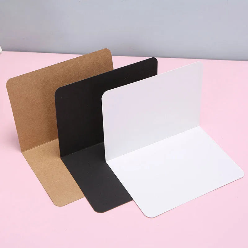 A pack of 100 blank folded kraft paper cards in 10x15cm size, shown in black, brown, and white colours.