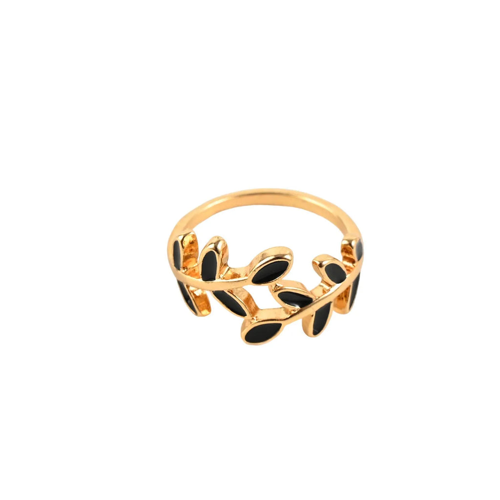 Gold-coloured acrylic ring with a geometric leaf and floral design on a white background.