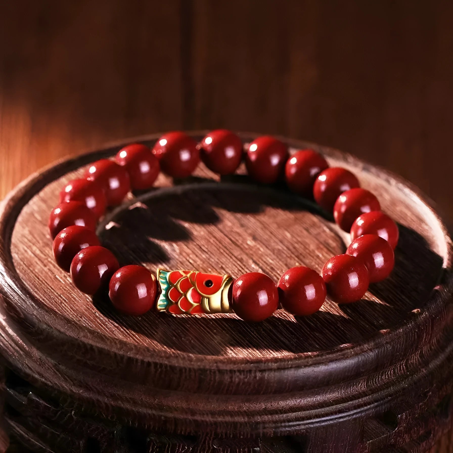 Handmade natural cinnabar koi bracelet with gold balls on a bead, showing traditional Chinese style.