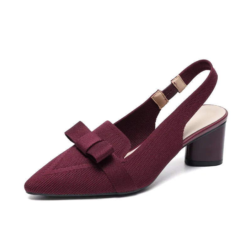 Women's closed toe high heel sandals with bow detail, ankle buckle strap, and pointed toe in a solid colour.