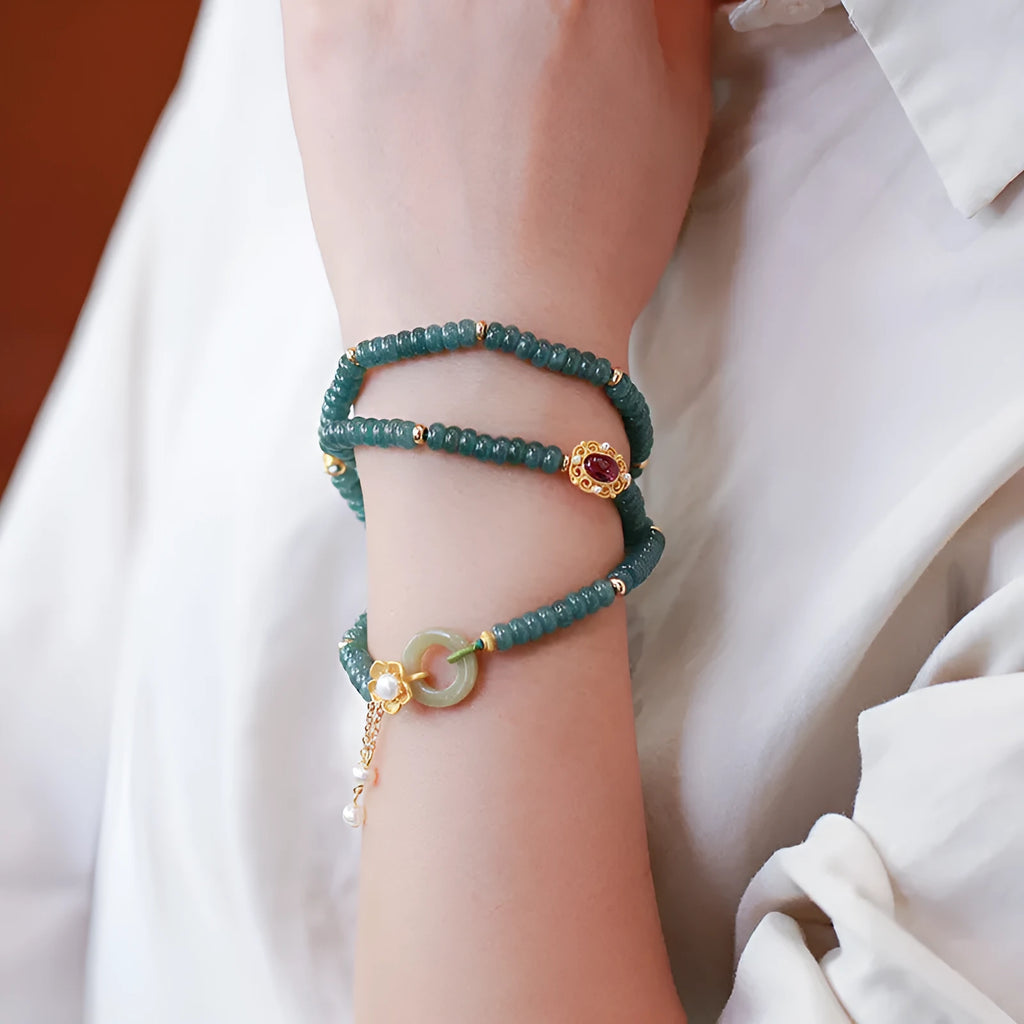 Close-up of a women's blue water jade abacus bead bracelet with three rings, tourmaline, and pearl accents.