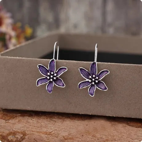 A pair of purple flower-shaped alloy stud earrings with a simple post back, shown against a plain background.