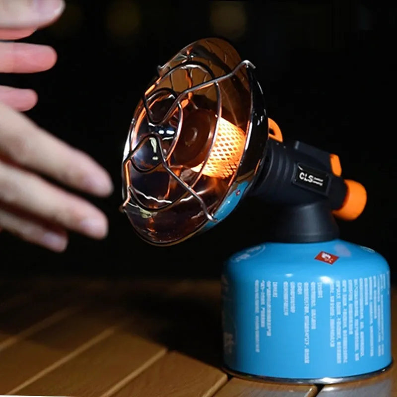 Black and orange portable outdoor gas heating stove with automatic ignition on a camping table.