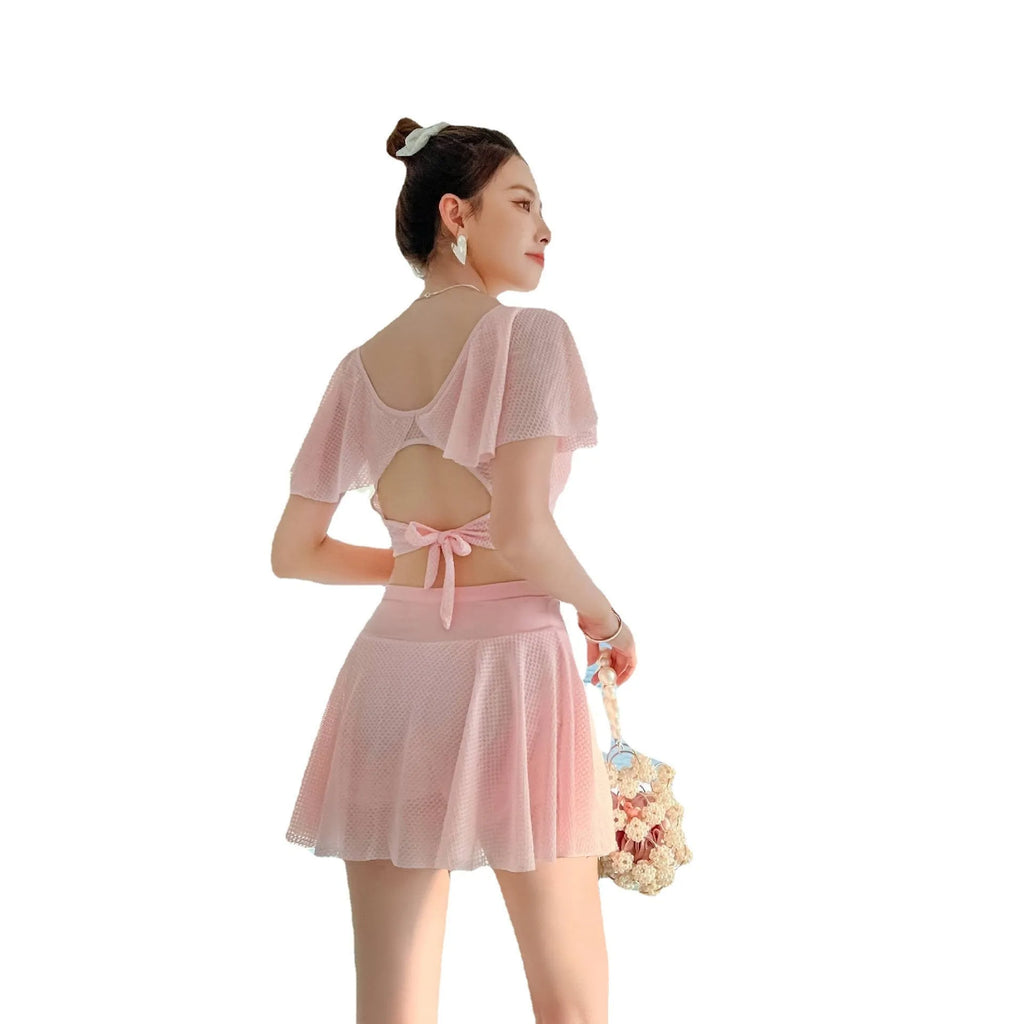 White two-piece women's swimsuit with a skirt bottom, shown alongside black and pink colour options.