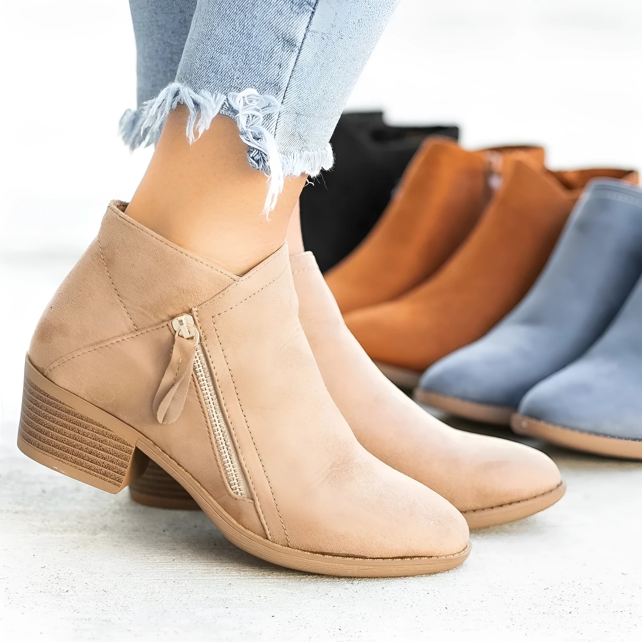 Women's beige suede ankle boots with a side zip and chunky heel on a plain background.
