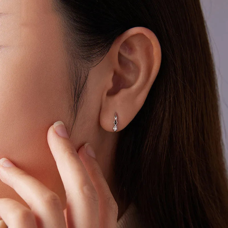 Close-up of S925 sterling silver rhombus earrings with diamond plaid pattern on a neutral background