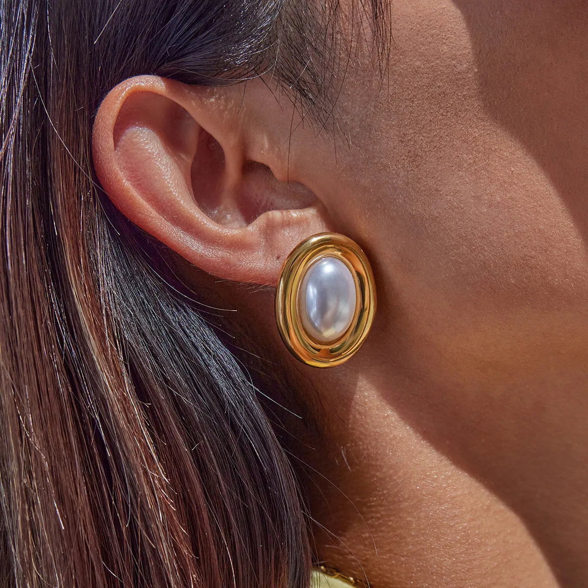 Close-up of a pair of women's stainless steel vintage pearl ear studs with a silver-toned post on a white background.