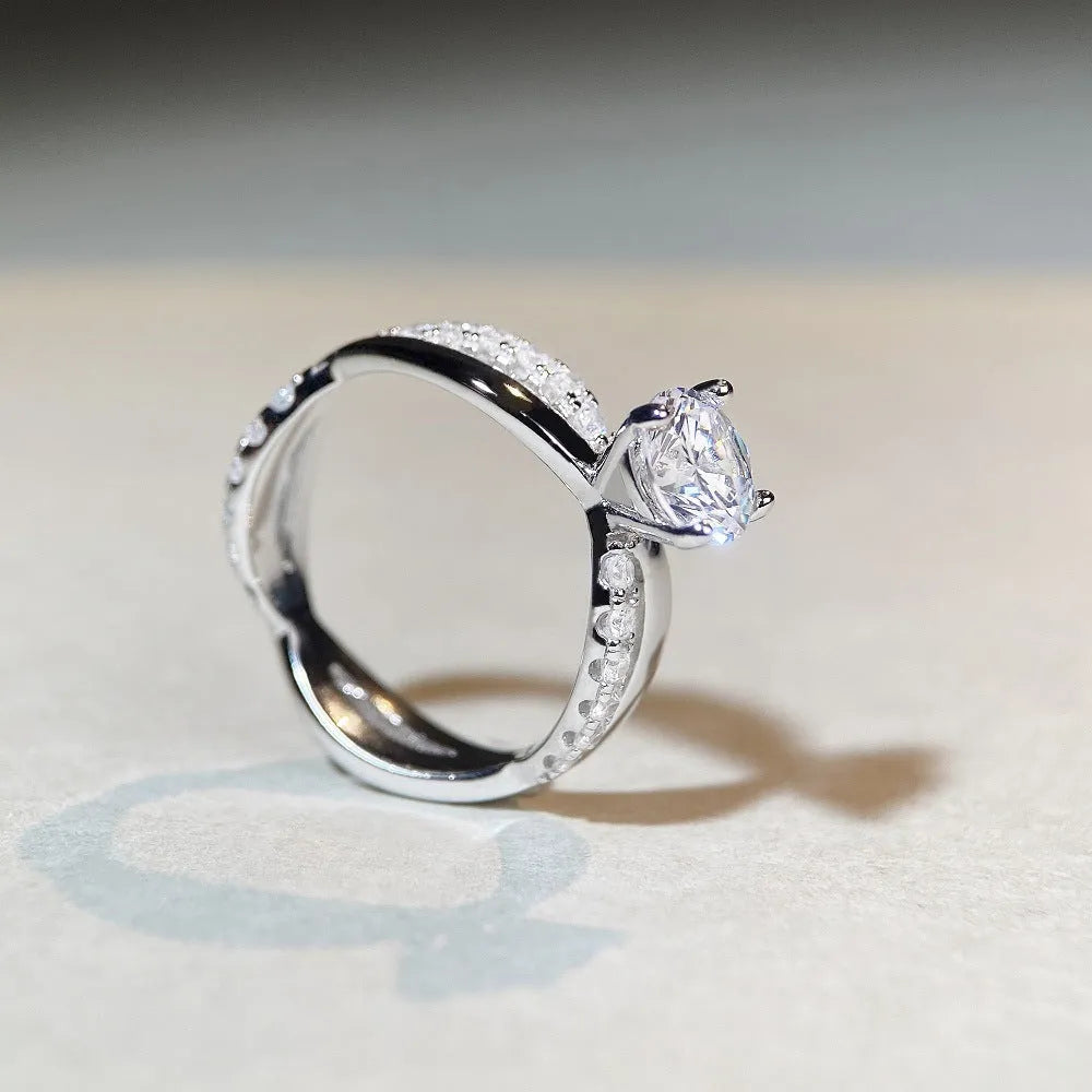 Geometric silver ring with a 1 karat moissanite stone in a four-claw setting and twisted arm band.