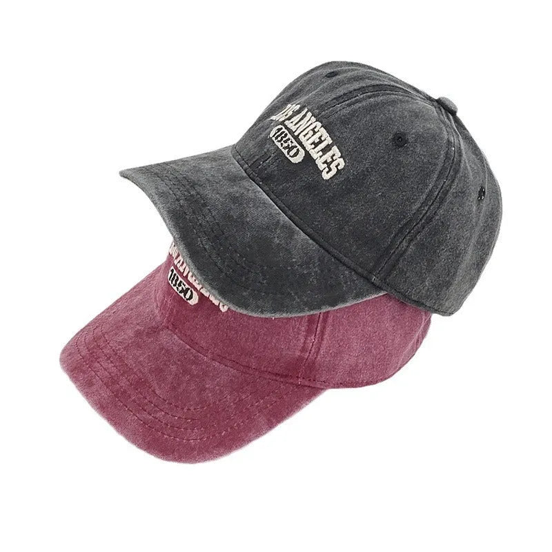 Retro style acrylic peaked cap with distressed letter embroidery on the front, shown in beige colour.