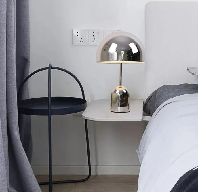 Modern mushroom table lamp with metal base in rose gold finish on a wooden table.