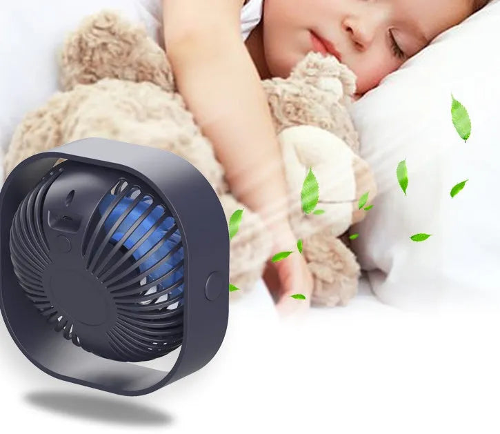 A small, modern USB desk fan in blue with a rotating head on a white desk.
