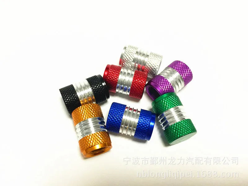 Seven aluminium alloy tyre valve dust caps in black, blue, gold, green, purple, red, and silver on a white background.
