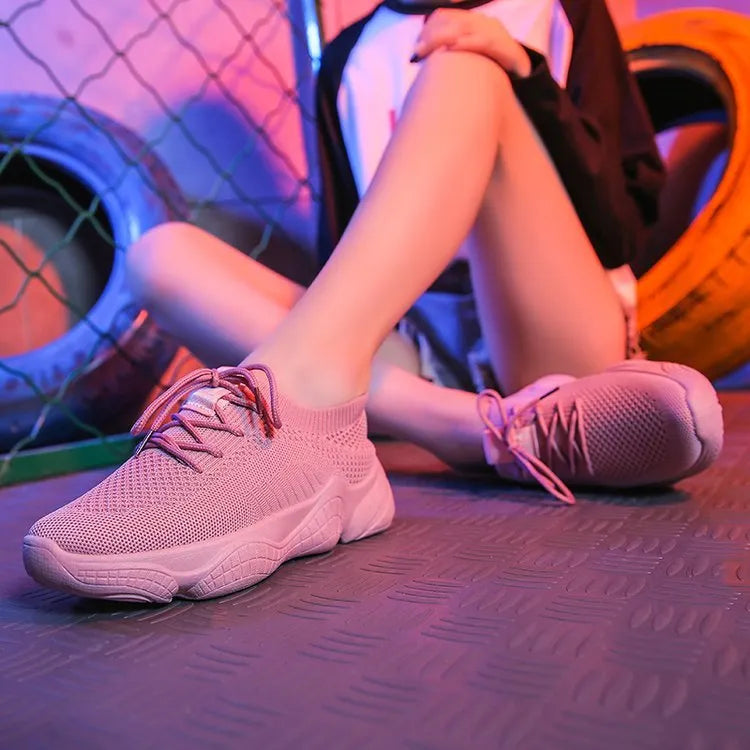 White thick-soled women's flyknit trainers with front strap and rubber sole.
