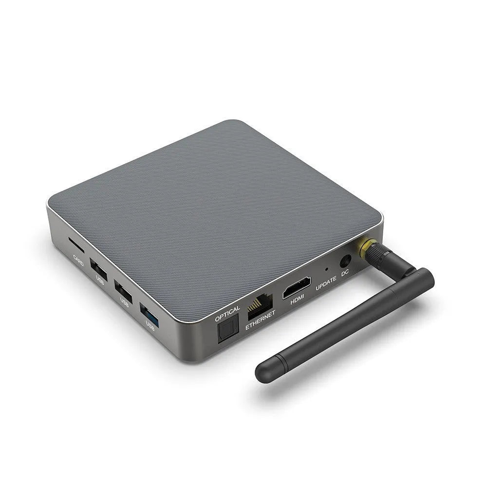 Black Android TV set-top box with HDMI port and remote control on a wooden surface.