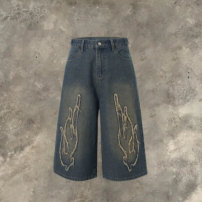 Men's black cropped denim shorts with orange flame embroidery patch on leg