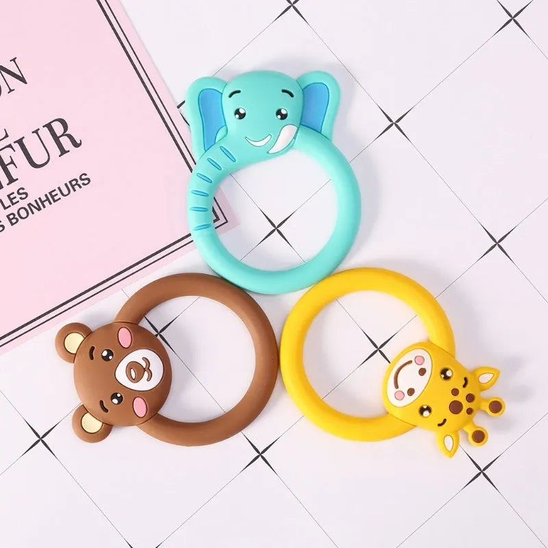 Three silicone baby molar teethers in brown, blue, and yellow on a light background