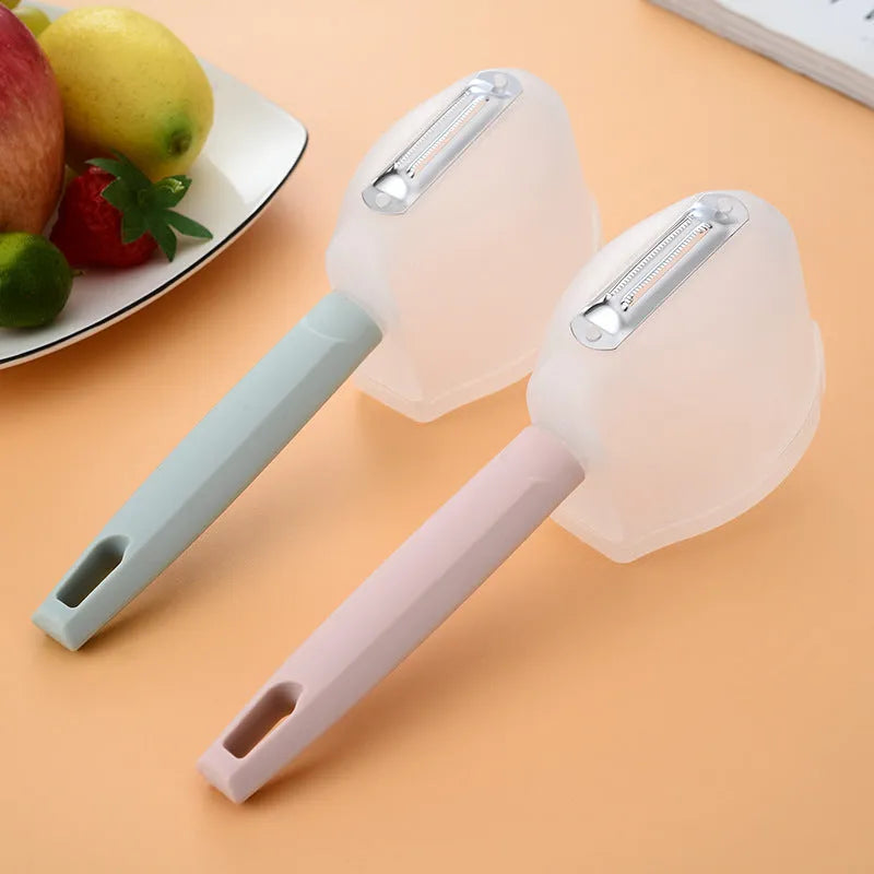 Stainless steel fruit peeler with pink plastic PP handle on light background