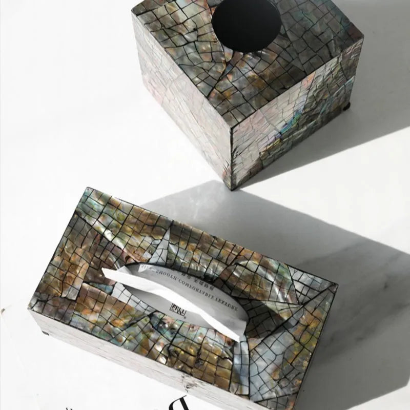 A black square natural shell storage box with a removable white internal organiser on a wooden table.