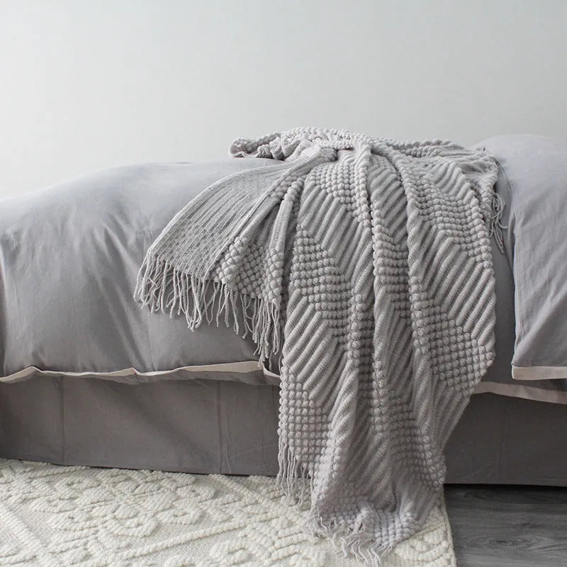 Small polyester fibre throw blanket in dark grey, shown folded, dimensions 127cm by 170cm.