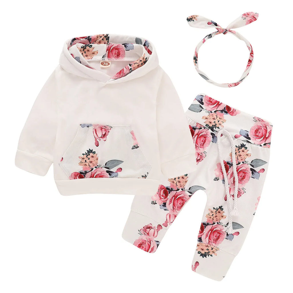 White cotton hooded pantsuit for a baby girl on a hanger, showing long sleeves and full-length trousers.