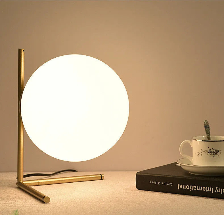 Creative desk lamp with glass shade and three-tone LED light on a desk, showing push button switch and cable.