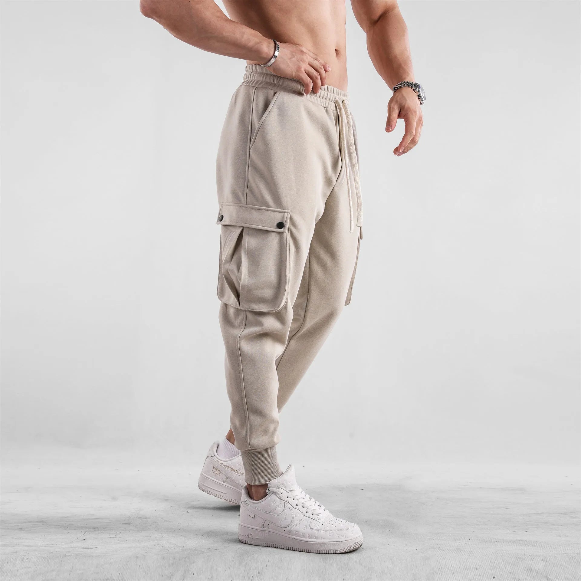 Men's loose light grey cotton trousers with ankle ties and multiple pockets laid flat.