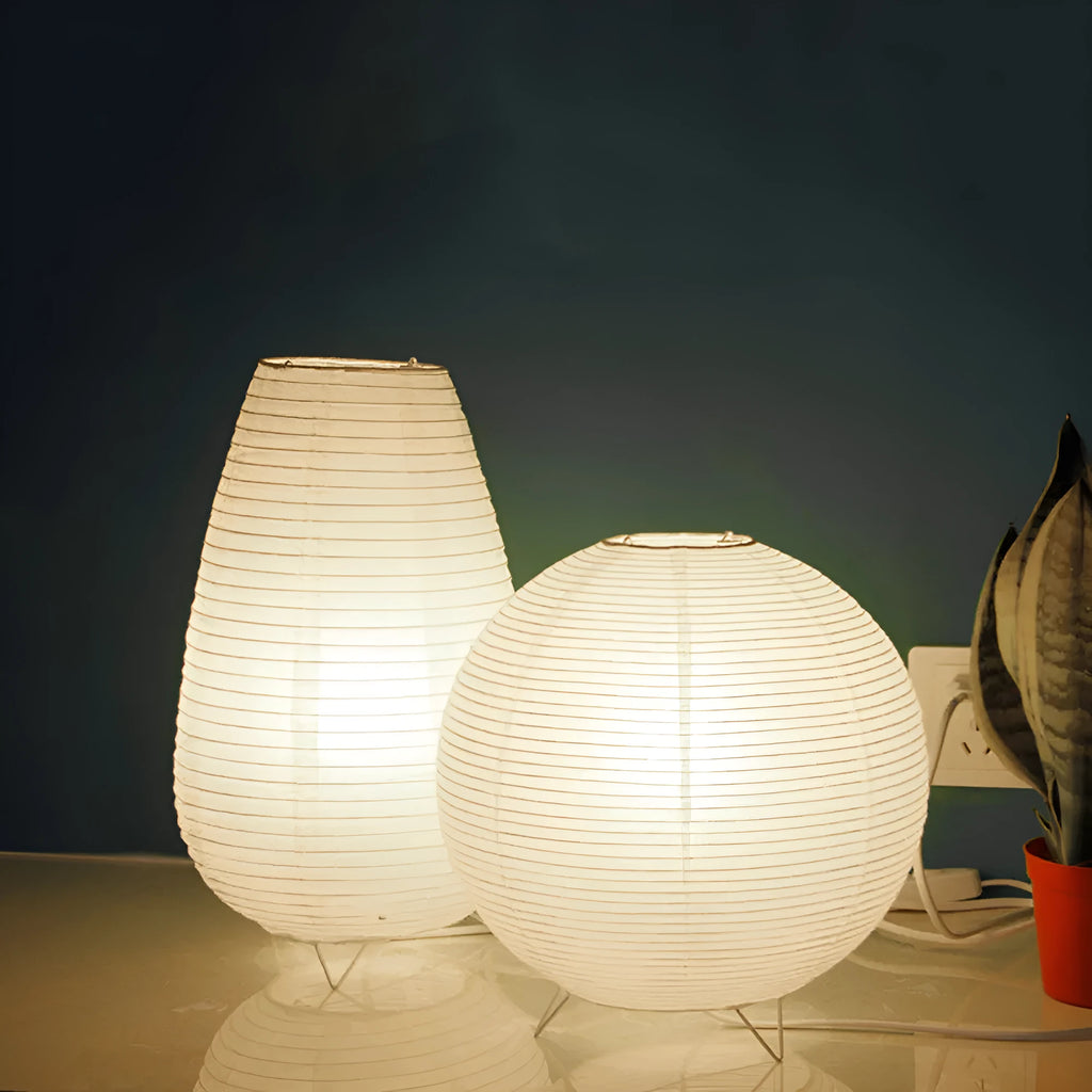 White handcrafted rice paper table lamp with either a circular or rectangular shade on a wooden desk.