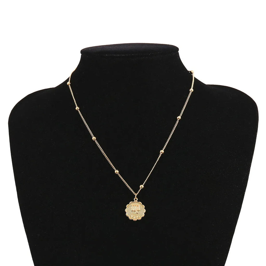 Gold plated metal zodiac constellation pendant necklace with bead chain on white background