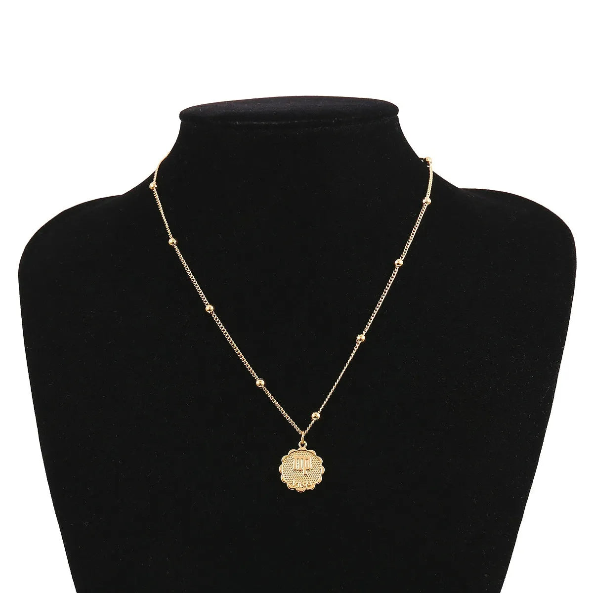 Gold plated metal zodiac constellation pendant necklace with bead chain on white background