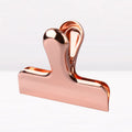 Gold stainless steel dovetail clip holding a stack of papers on a desk