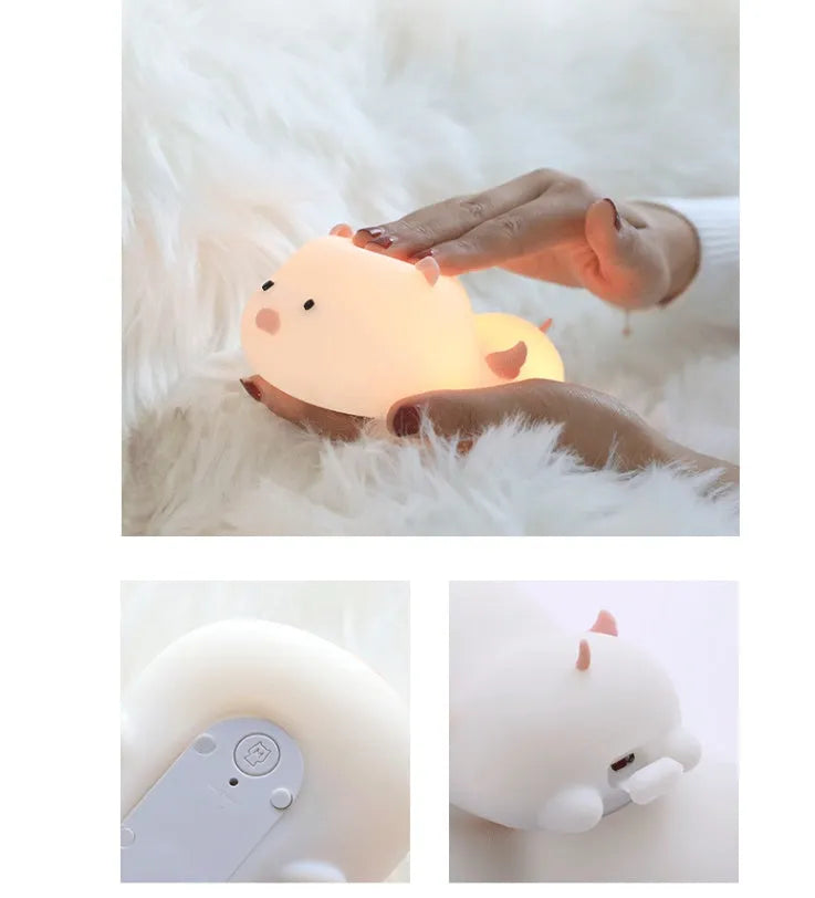 Blue silicone pig-shaped rechargeable LED night light with touch control on a wooden surface.
