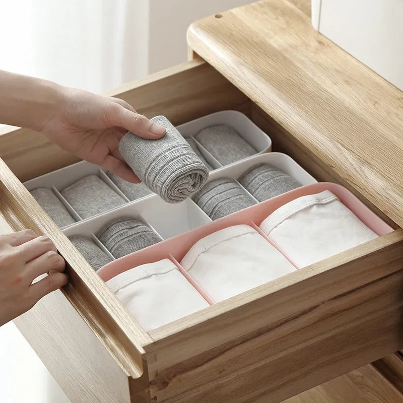 PP plastic socks and underwear storage box with grid compartments in apricot colour on a desktop