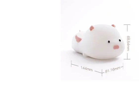 Blue silicone pig-shaped rechargeable LED night light with touch control on a wooden surface.