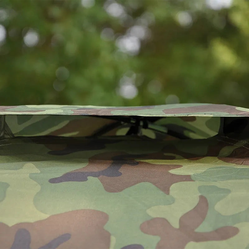 Green camouflage two-person camping tent with triangular skylight and fibre glass poles pitched outdoors.