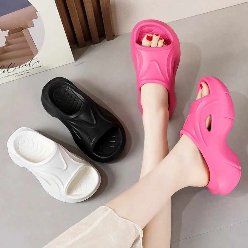 Women's white thick-soled EVA slippers with round toe on a beach background.