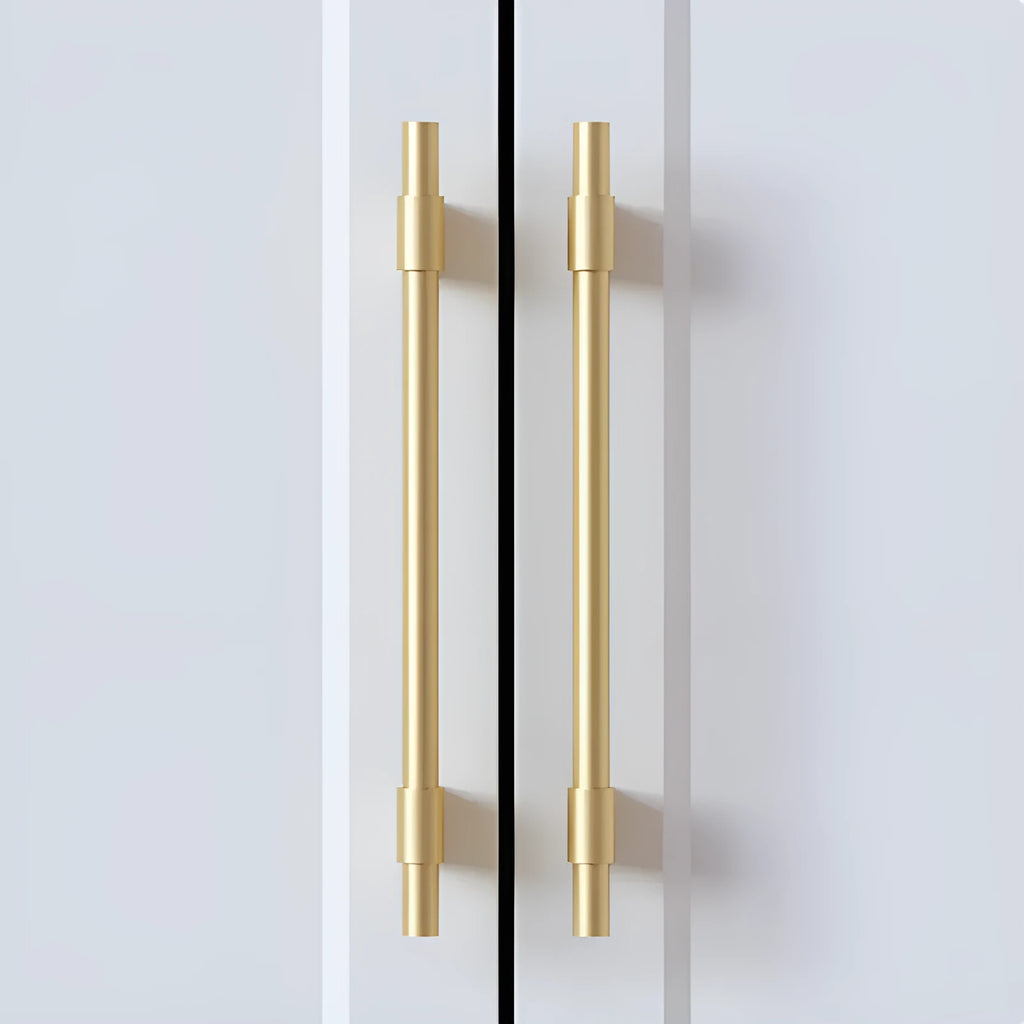 Gold brass single hole drawer handle on white cabinet door – minimalist metal pull