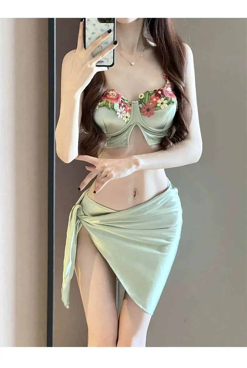 Green women's three-piece bikini set with triangle top, briefs, and skirt on white background