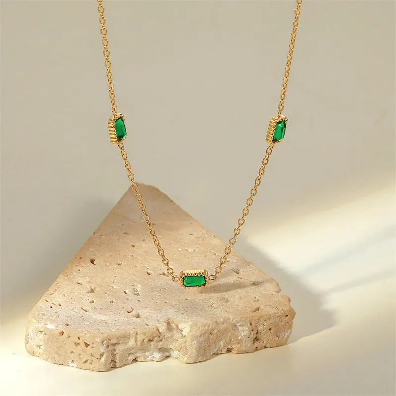 Titanium steel emerald zircon necklace and bracelet set with gold hardware and O-ring chain on a white background