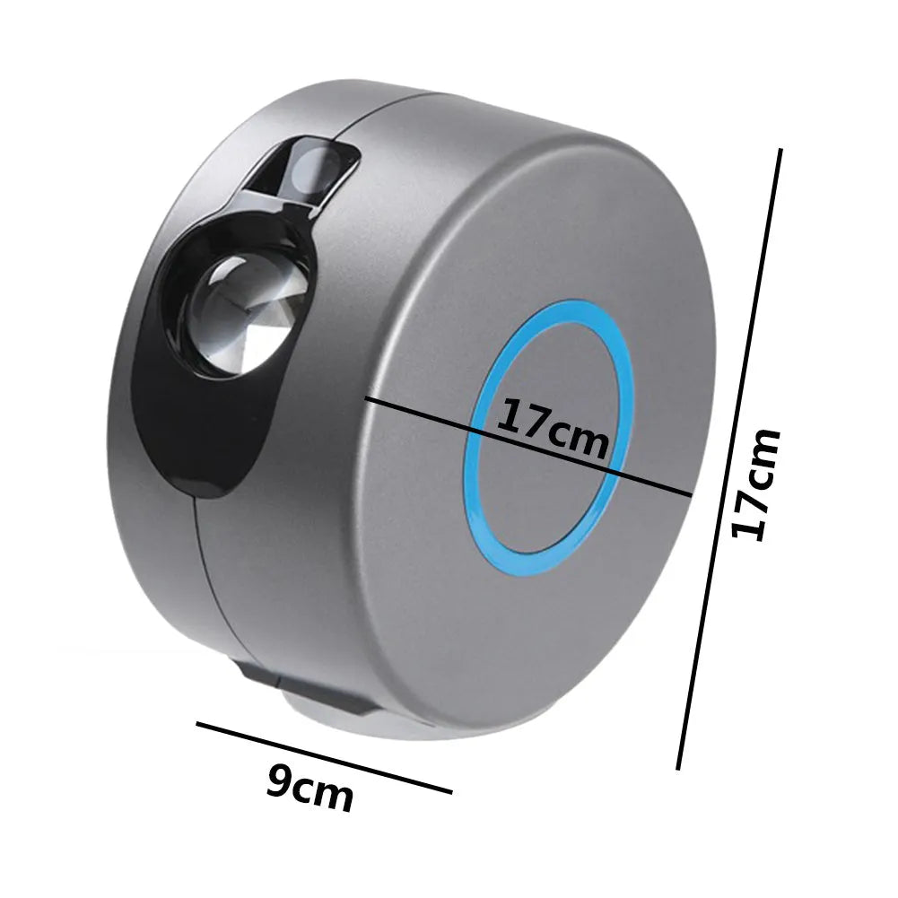 Grey starry sky projection lamp with remote control on a table, projecting colourful light dots on a dark wall.