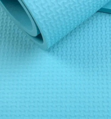 Red EVA fitness yoga mat rolled up next to its storage bag, showing textured surface.