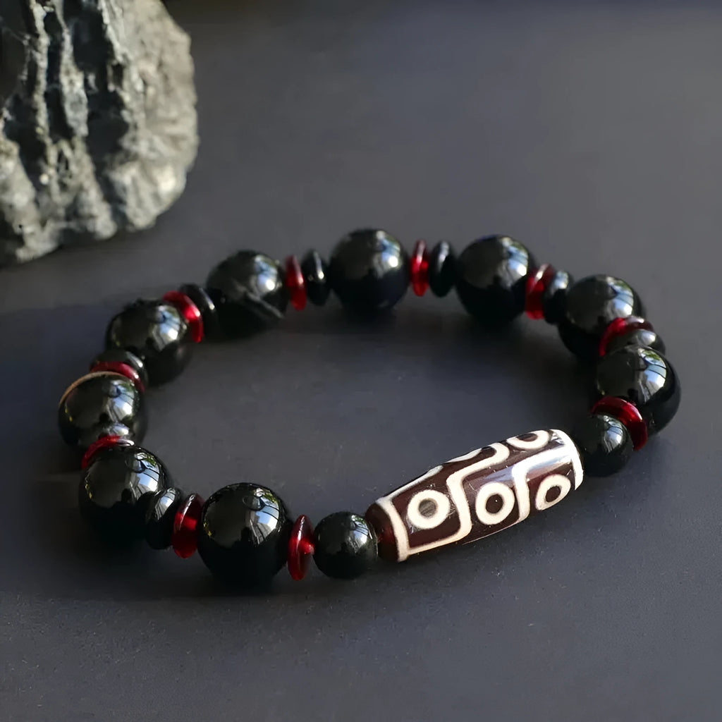 Hand-woven black agate Dzi bead bracelet with chalcedony detail on a wrist.