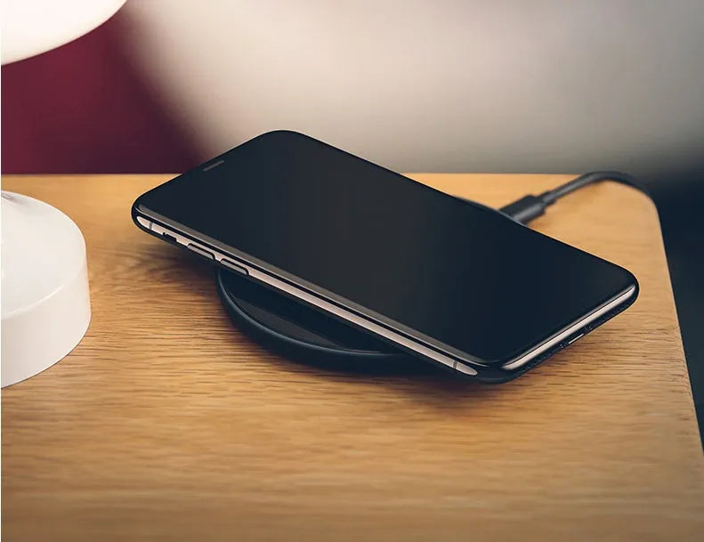Black or white glass disc wireless charger on a surface, showing status light.