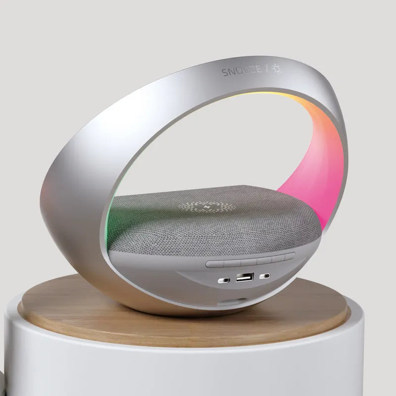 Beige multifunctional bedside unit with wireless charging pad, Bluetooth speaker, and LED light on a wooden table.