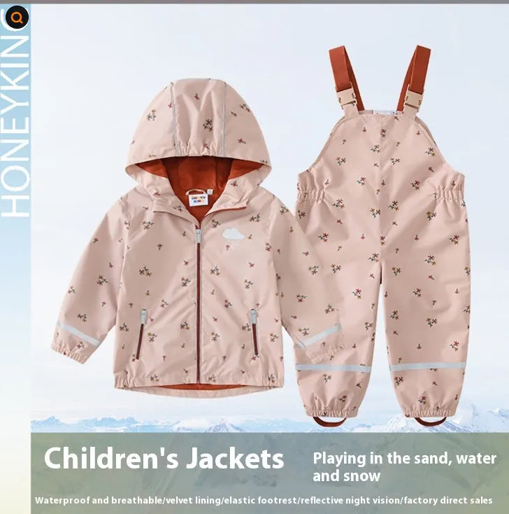 Pink floral children's rain jacket and pants set with hood, reflective details, and loose fit on a child outdoors