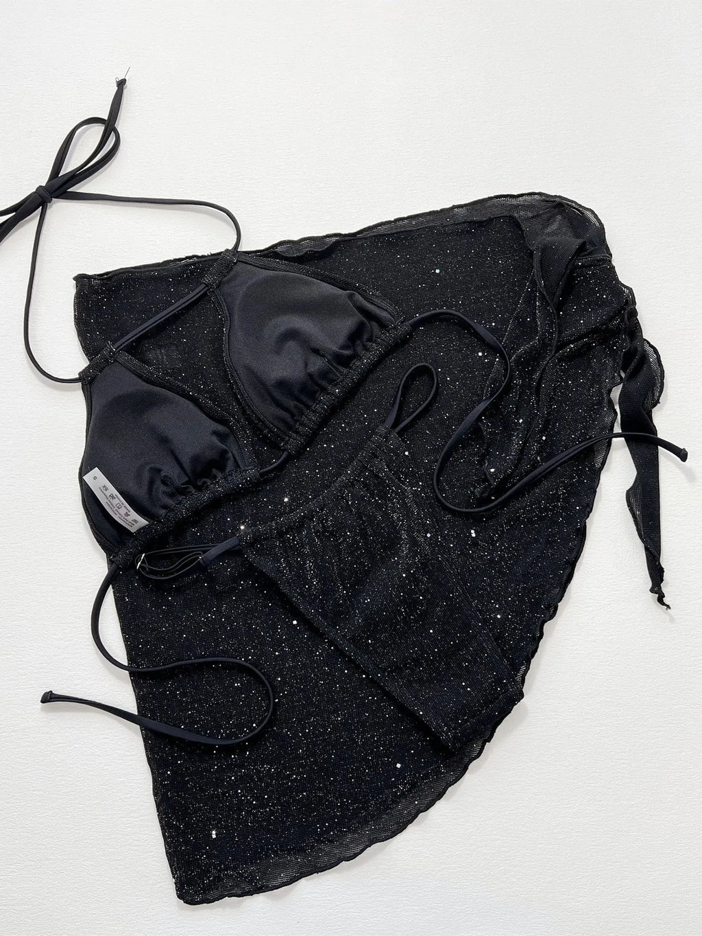 Black three-piece bikini swimsuit set with top and shorts on a plain background.