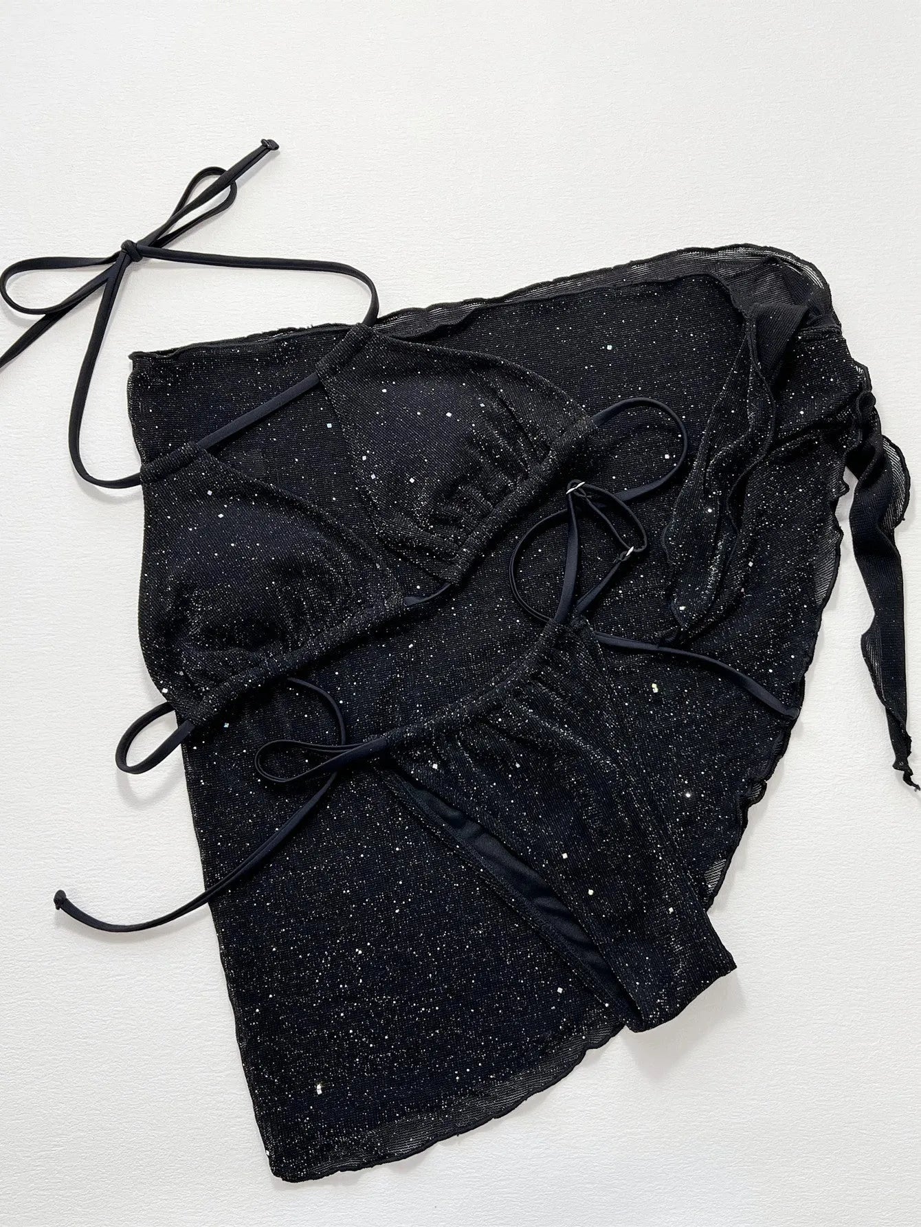 Black three-piece bikini swimsuit set with top and shorts on a plain background.