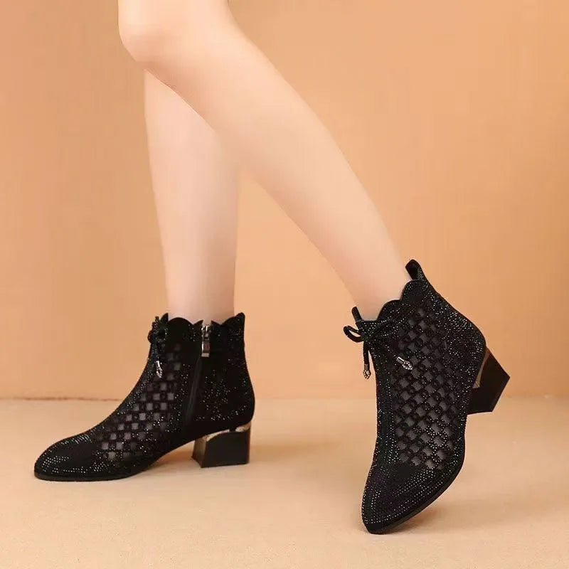 Women's black cutout mesh ankle boots with mid heel and rhinestone trim, side zipper closure