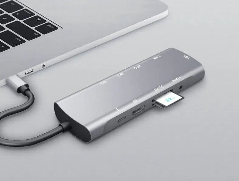 Grey aluminium USB-C docking station with HDMI, VGA, and USB ports on a desk.