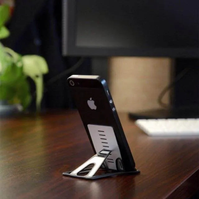 Black card phone holder measuring 8.5cm by 5cm on desktop surface